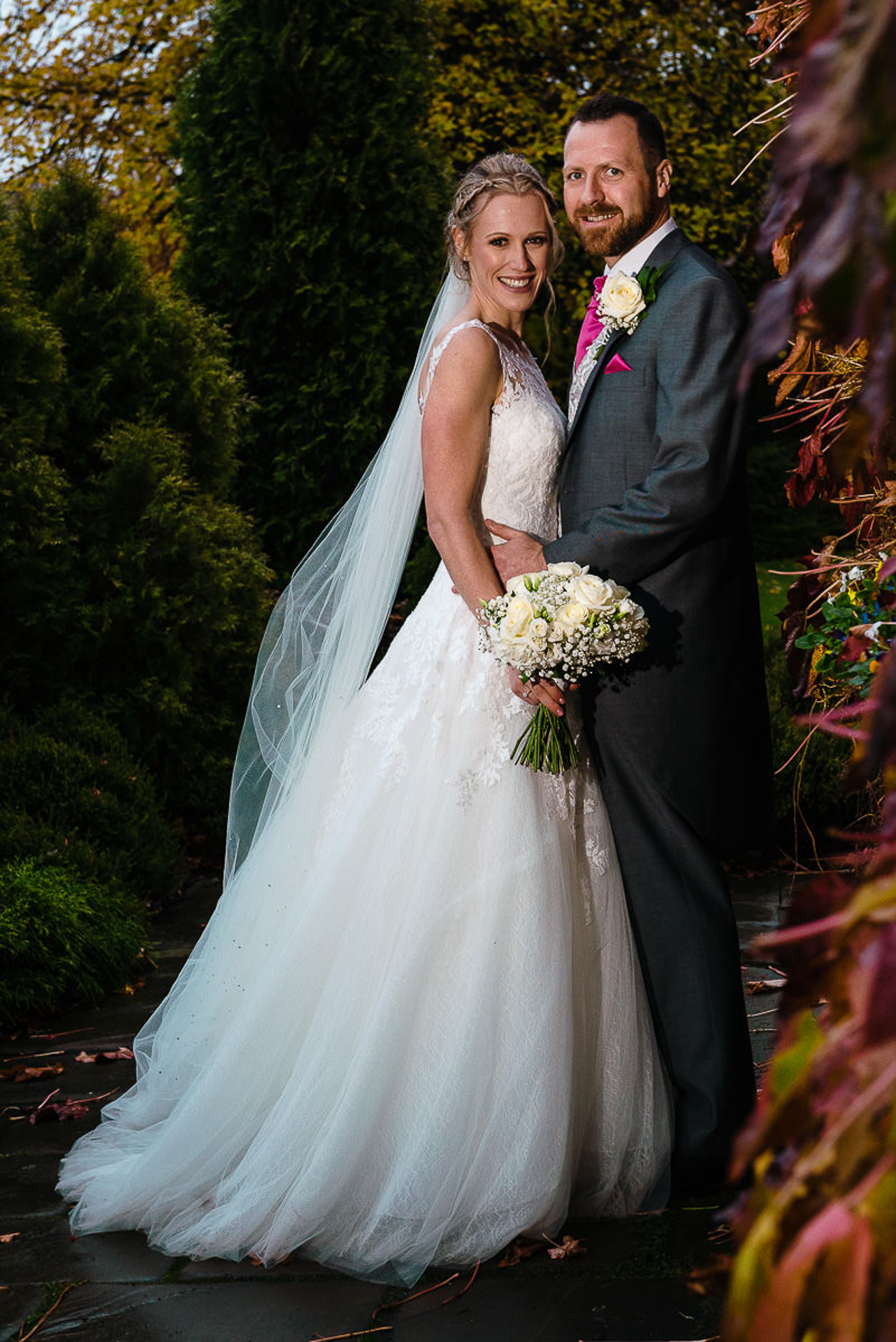 bride and groom by autumn leaves