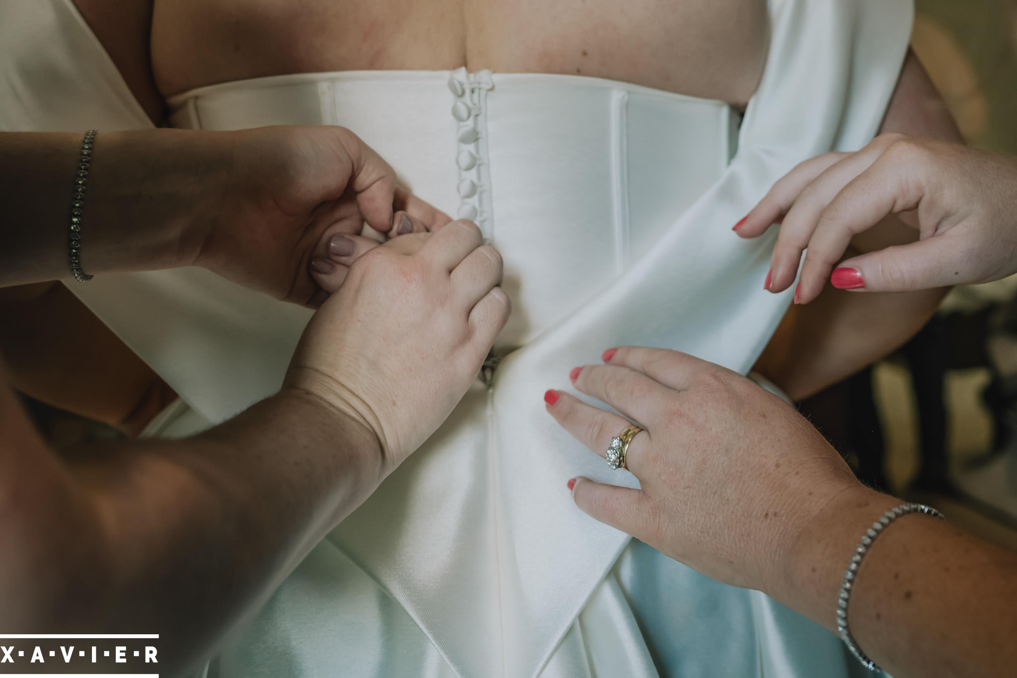 bridesmaids fasten the brides dress