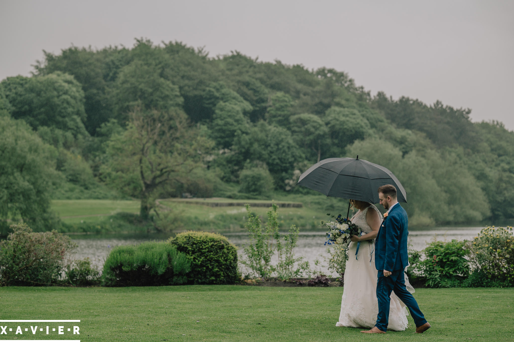 bride and groom walk under umbrella
