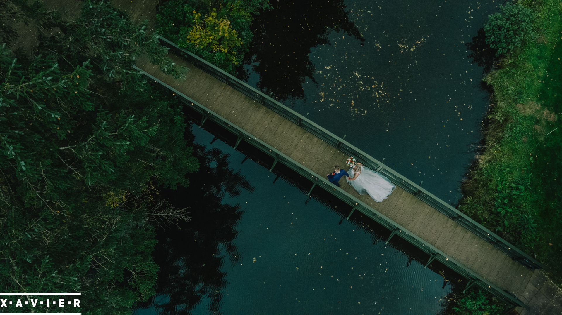 drone photo of bride and groom walking over the bridge