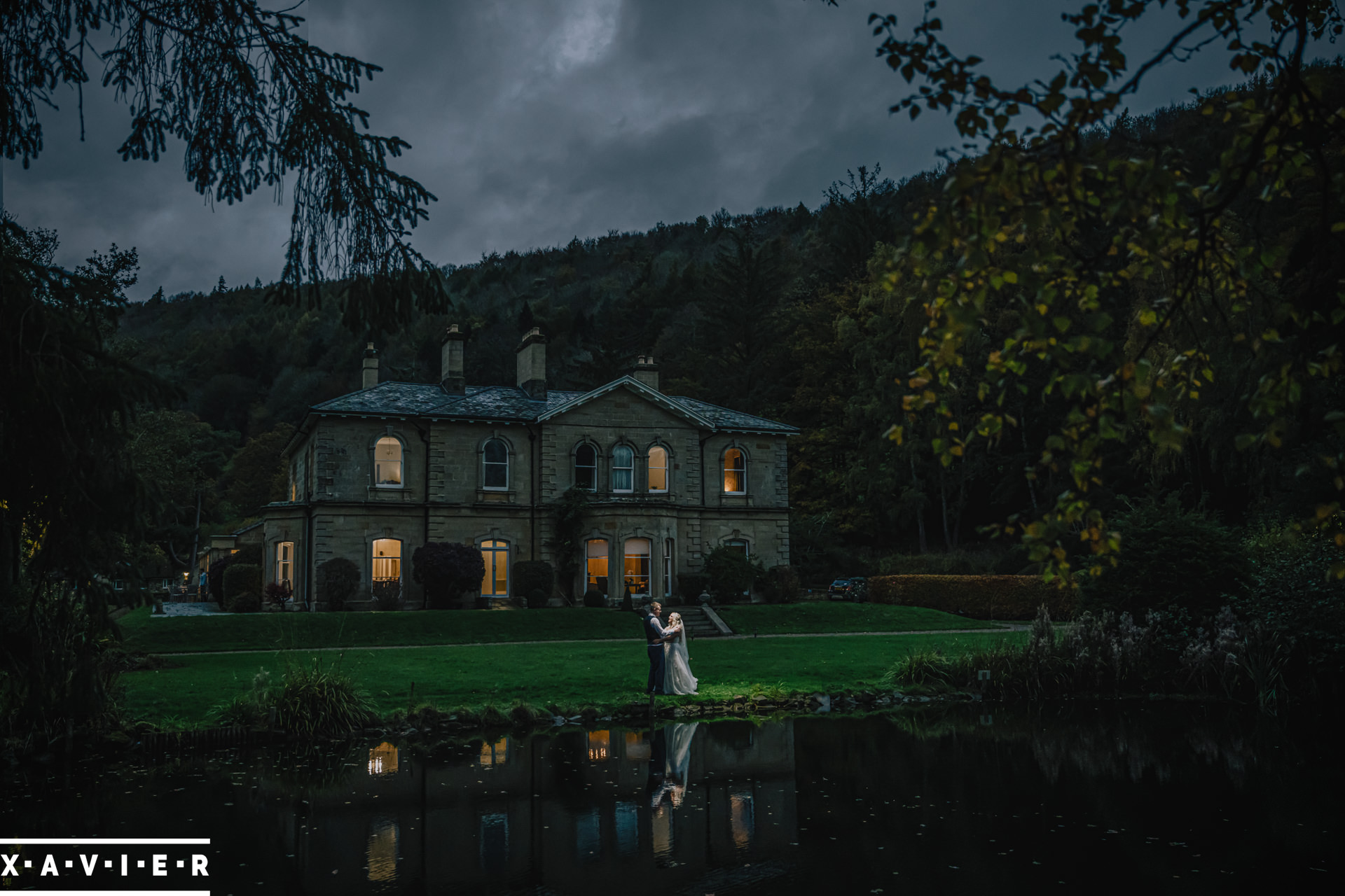 bride and groom stand in front of hotel with reflection