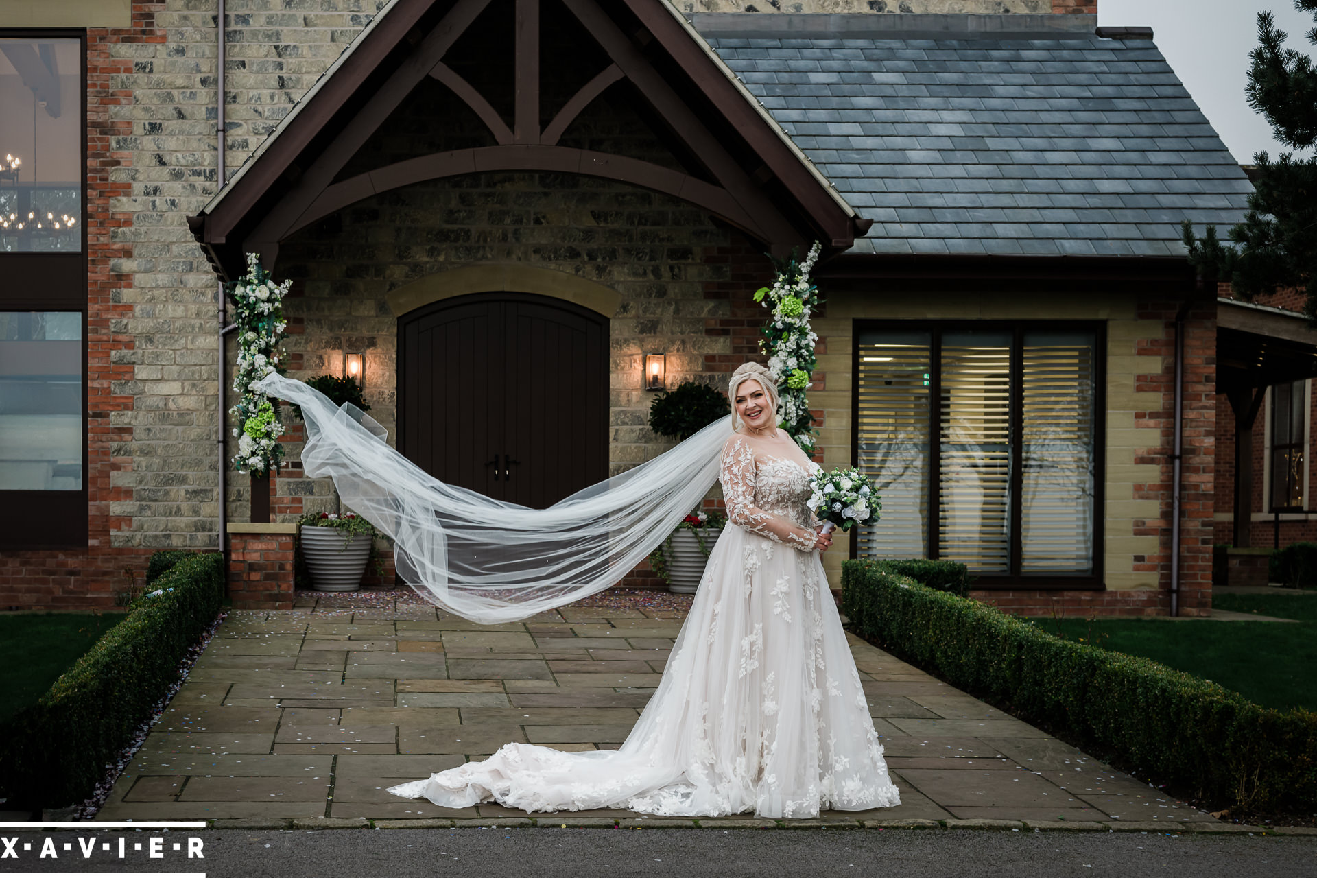 bride poses with veil outside the chapel