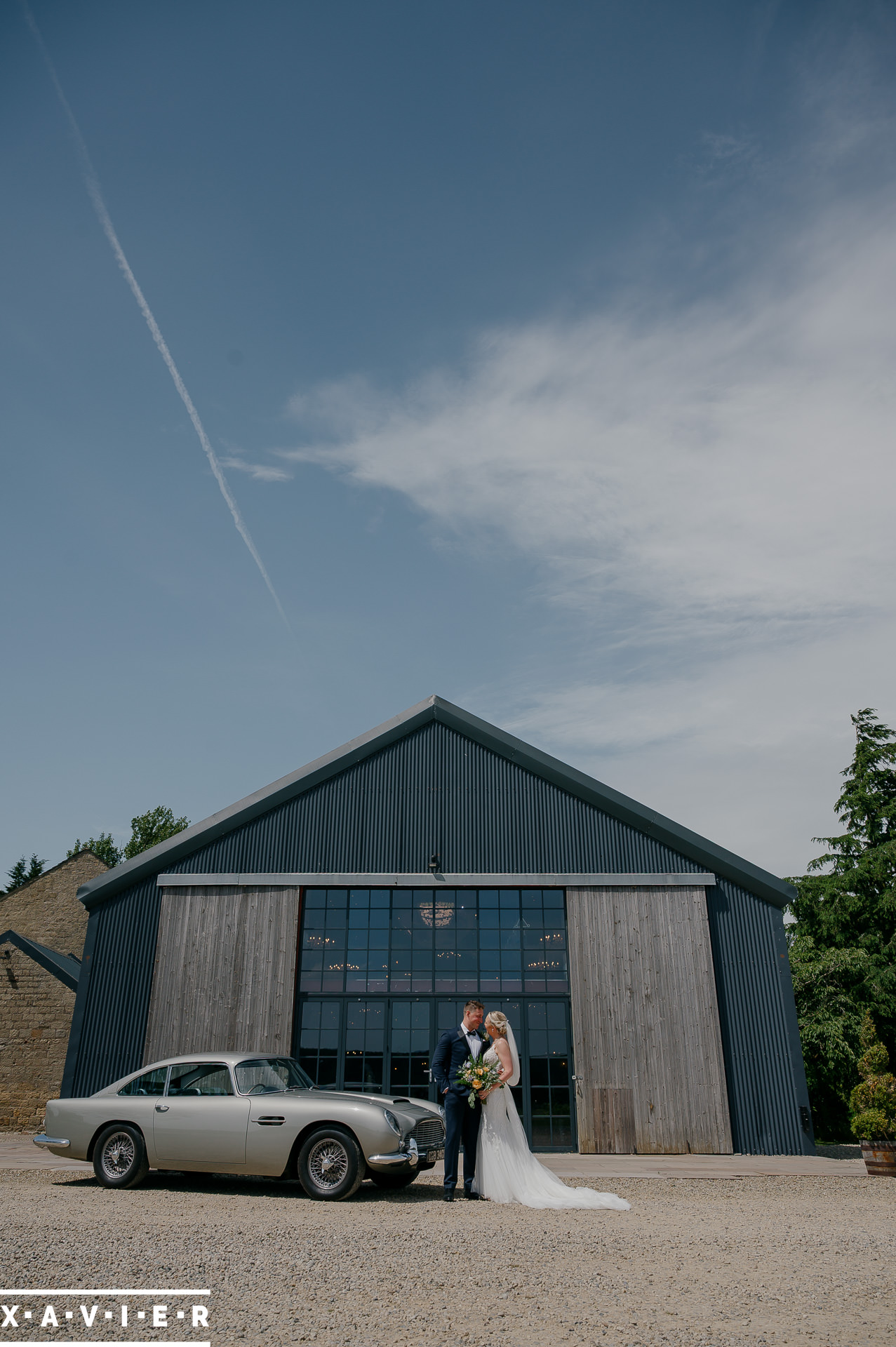 bride and groom standing in fornt of venue with wedding car