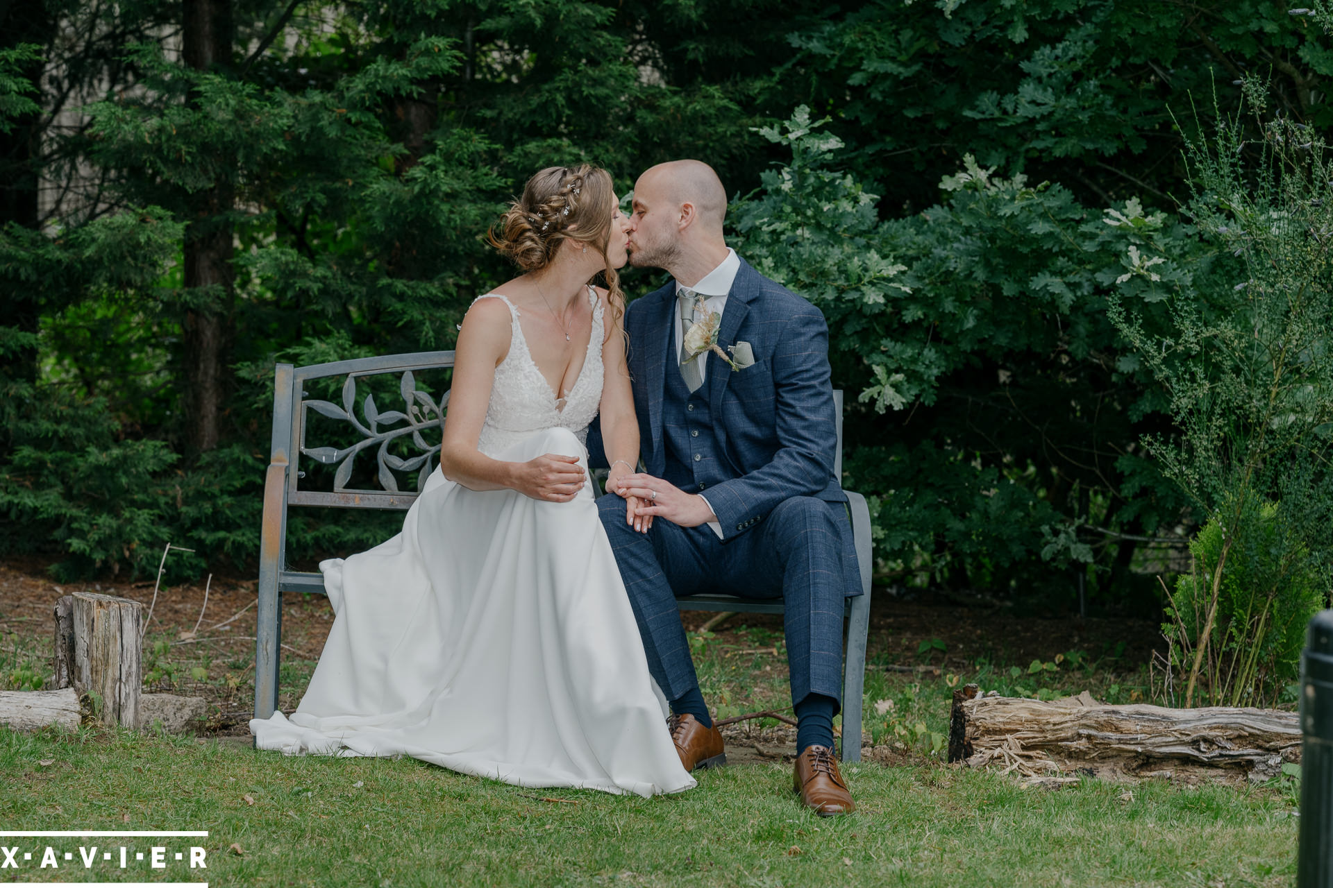 bride and groom kiss on the bench