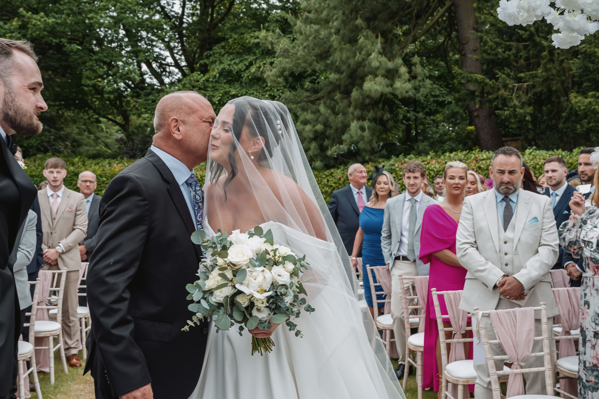 father kisses bride on the aisle