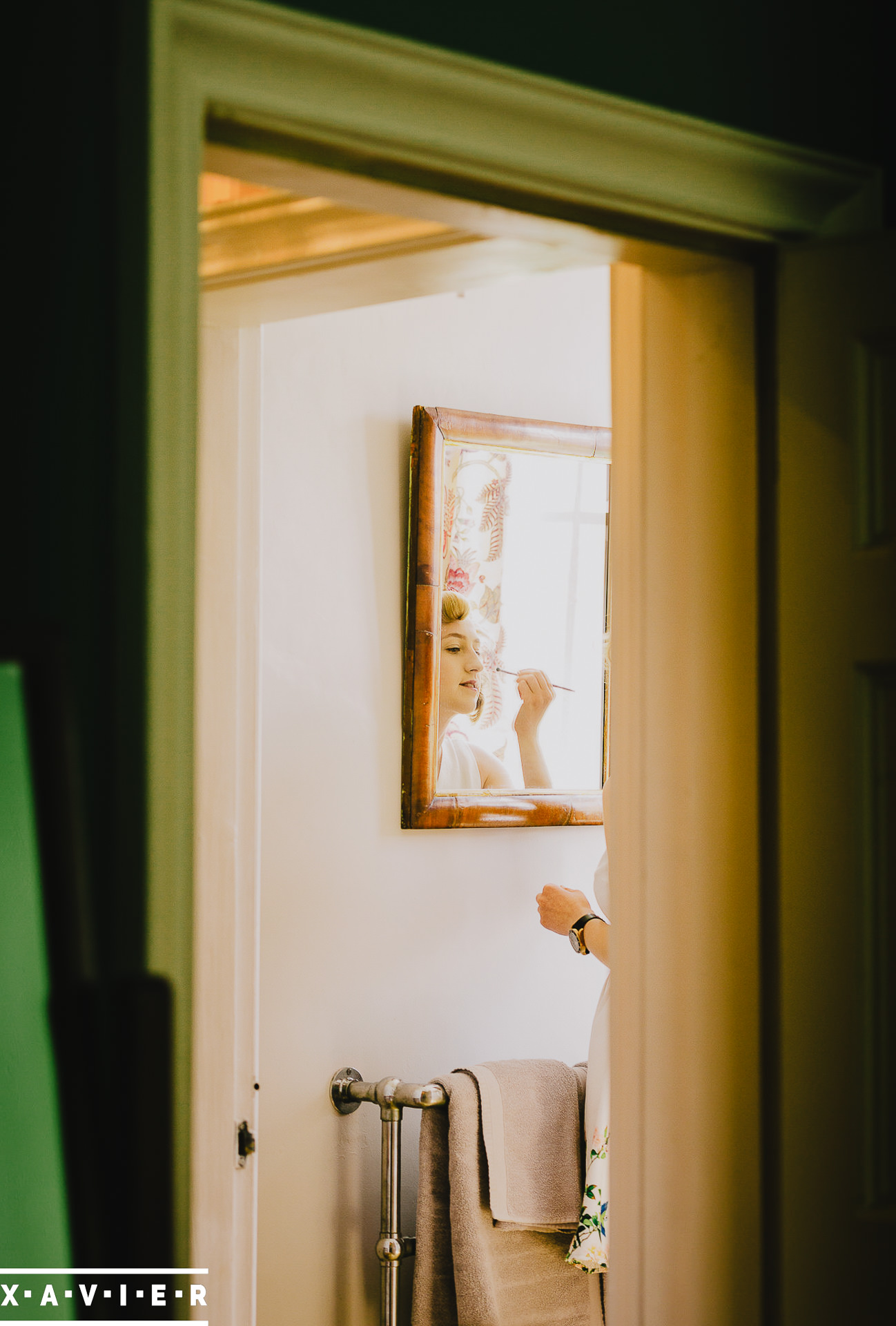 bride applies her make up in the mirror