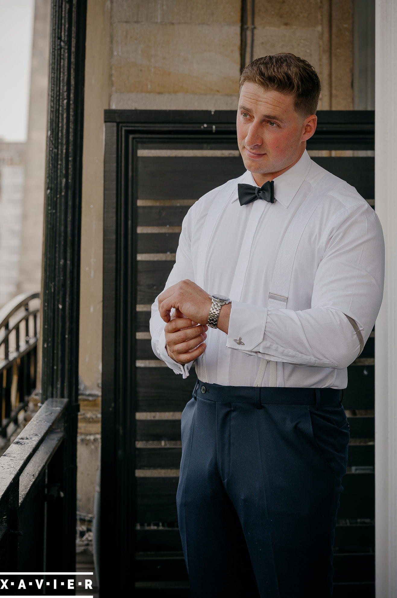 groom is fastening his wristwatch on the balcony