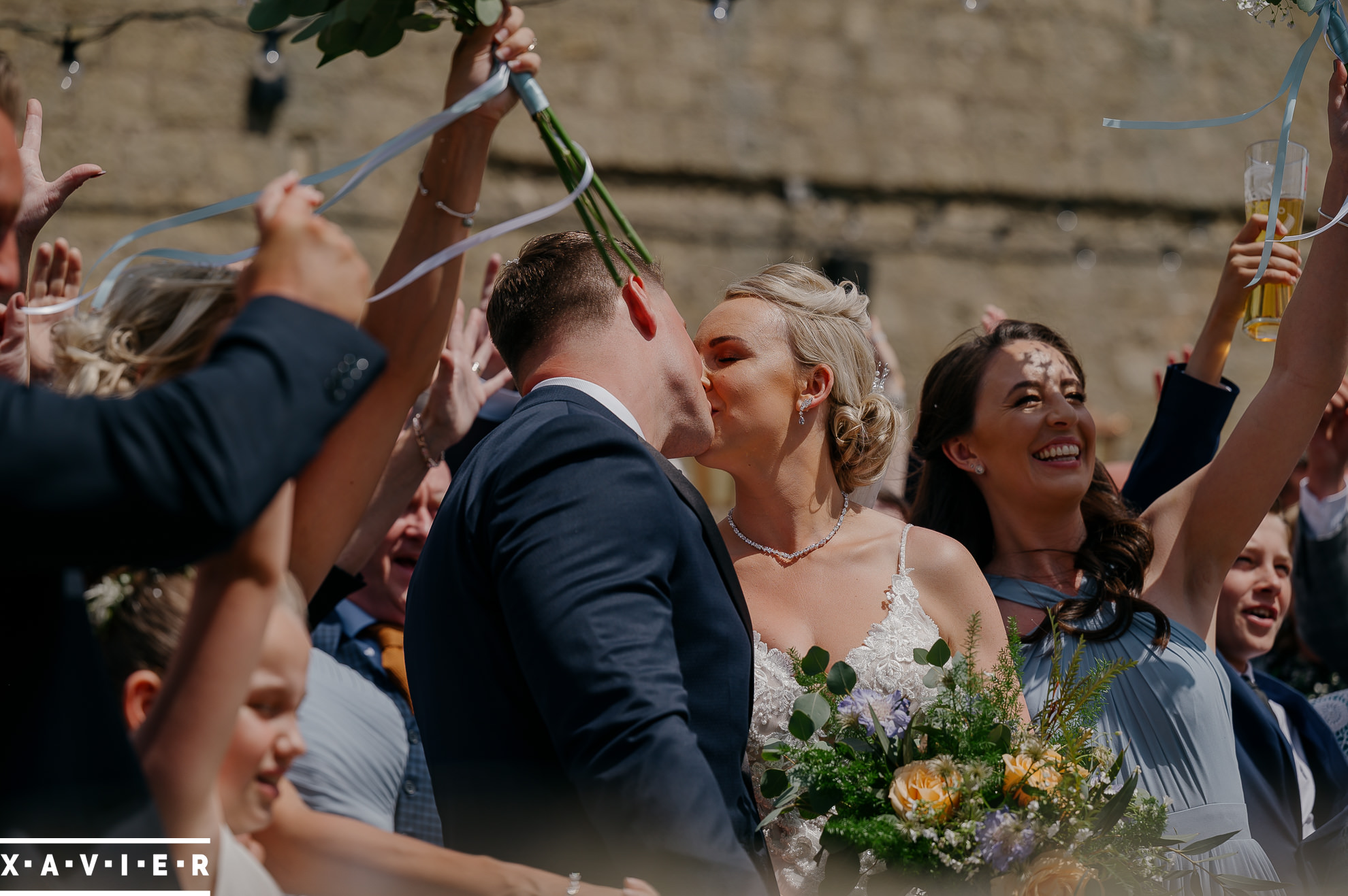 bride and groom kiss outside surrounded by guests