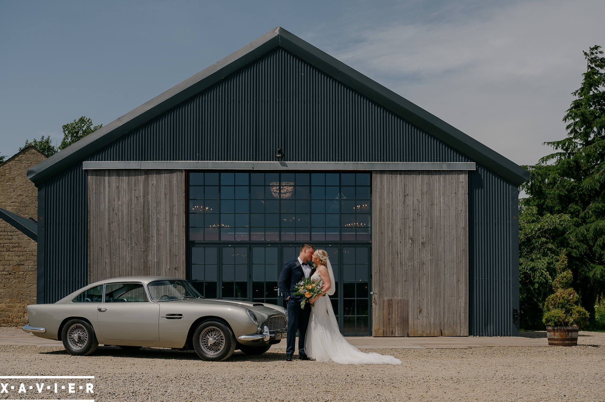 bride and groom outside the barn next to aston martin db5
