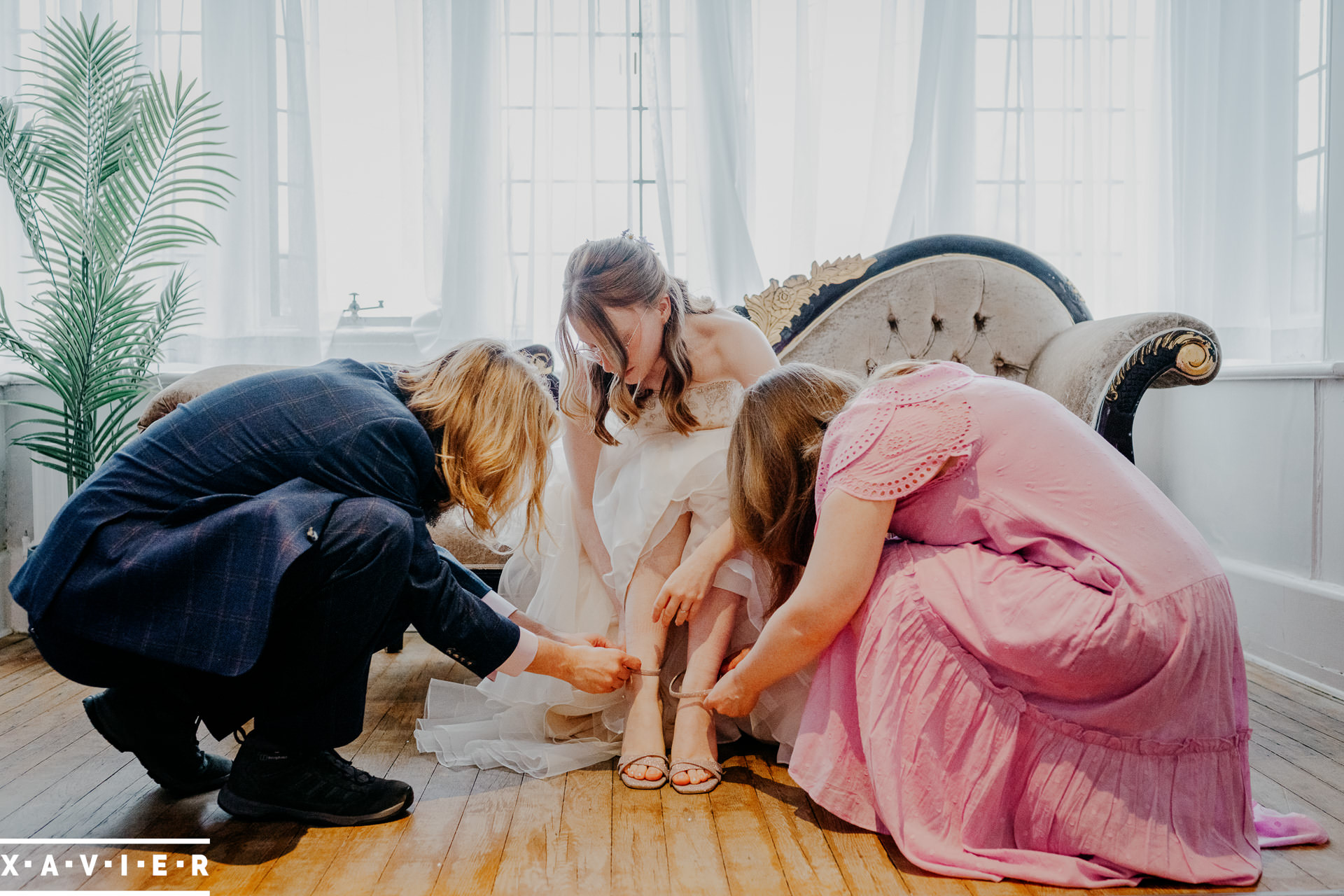bridal party fastening the brides shoes